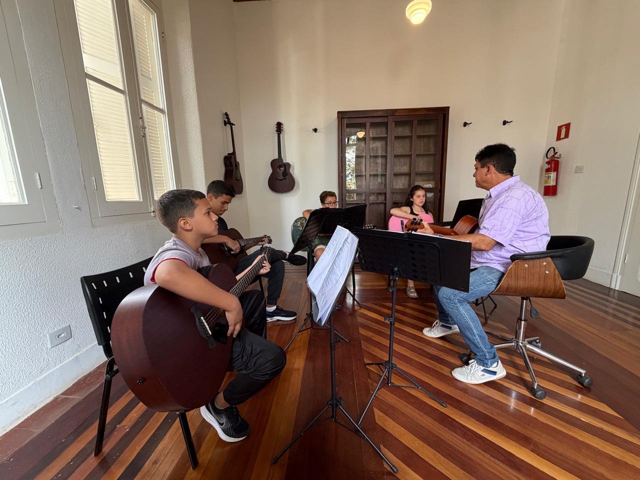 Turma de violão reunida com o professor na sala de aula
